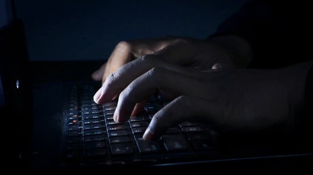 Night. Extreme close-up hands of unrecognizable hacker programmer working typing on keyboard laptop computer at dark room. Freelancer using laptop working from home, soft blue color.