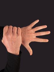 Man hand catching his own wrist of an open hand on a black background