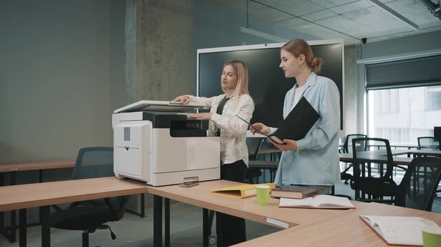 Office team collaborates at workplace around copier during busy work hours