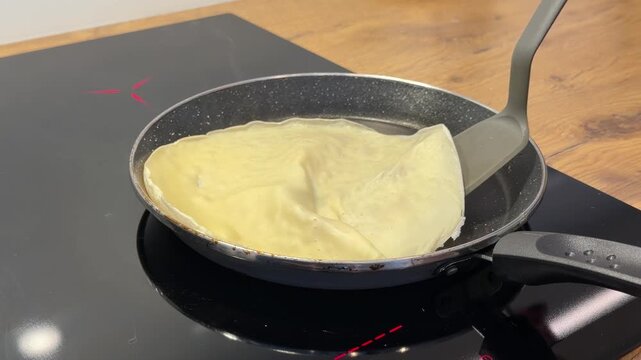Flipping a Golden Pancake in a Pan on an Induction Stove