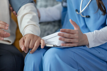 Close-up of nurse measuring blood pressure of elderly patient at home using digital...
