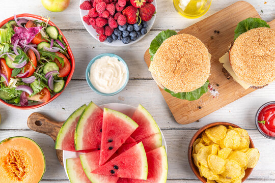 Tasty summer barbecue table with hamburgers, salads, fruits and snacks