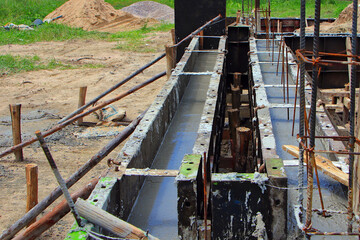 Newly poured concrete foundation beams at the construction site with steel bar reinforcement.