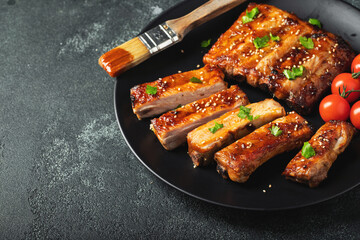 Hot grilled spare ribs from a summer BBQ served on a plate with sauce. Top view. Copy space