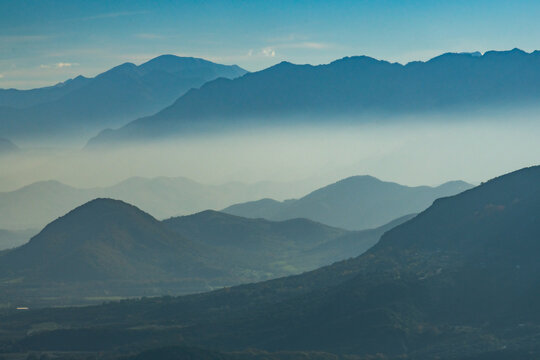 View of rolling hills and layered mountain ranges fade into a misty horizon, showcasing the natural beauty of the landscape, Trikala, Thessaly, Greece.