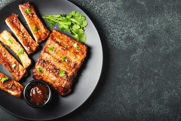 Hot grilled spare ribs from a summer BBQ served on a plate with sauce. Top view. Copy space