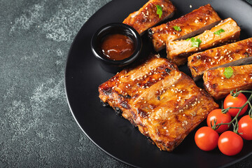 Hot grilled spare ribs from a summer BBQ served on a plate with sauce. Top view. Copy space