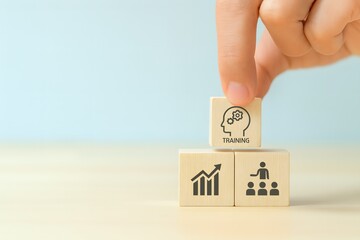 A hand carefully places a block with a brain and training icon onto a stack of business concept cubes