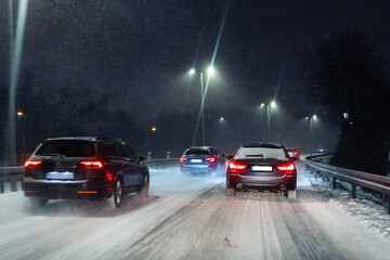 Winter traffic jam on snowy highway road night with long queue car, glowing red taillights, icy asphalt, falling snow, poor visibility and stressful commute conditions. Cold city transport atmosphere