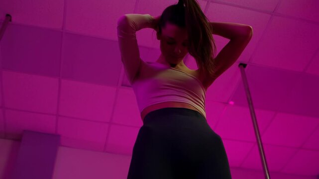 Sensual pole dancer performing in pink neon light