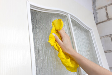 A woman washes a window with a rag.