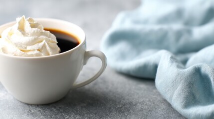 Freshly brewed coffee with whipped cream beside a soft cloth