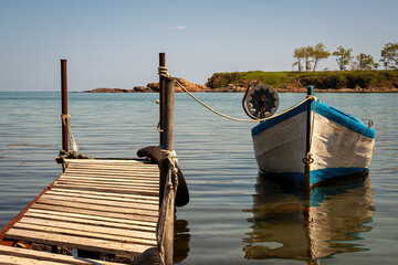 Old Wooden Pier with Fishing Boat Moored on Calm Sea. Coastal Scenery, Tranquil Seaside Landscape. Nautical Travel, Fishing Industry and Summer Holiday Concept