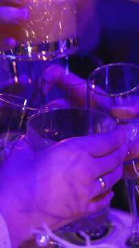 Group of guests celebrate and raise glasses, toasting and cheering with alcohol glasses with wine and champagne in the restaurant on corporate christmas birthday party event or wedding celebration