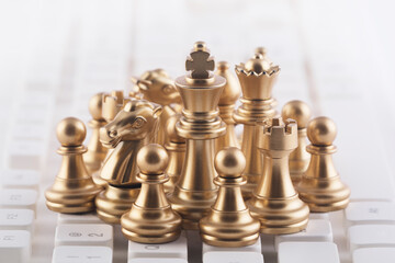 Group of luxury golden chess pieces on white computer keyboard