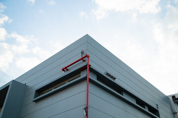 Height limit warning structure with industrial piping system under a clear sky.Red fire protection pipes and steel structure installed on a modern warehouse exterior.