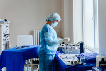 Nurse preparing surgical instruments near window in hospital operating room