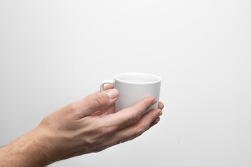 Męska dłoń trzymająca białą filiżankę. Zdjęcie na białym tle. © hunter76
