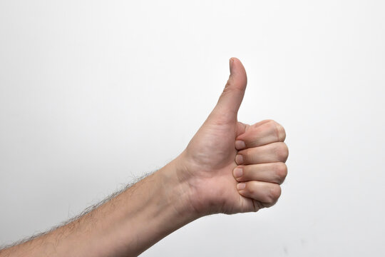 Męska dłoń pokazująca kciuk w g&oacute;rę. Zdjęcie na białym tle.
