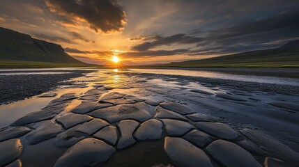 Sun sinks below the horizon casting golden light across a vast landscape of cracked earth and reflective pools