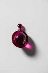 Single translucent red capsule with a drop shape on a clean white background