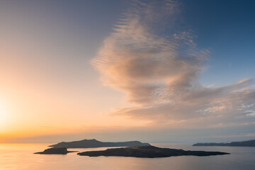 Beautiful sunset at Santorini island, Greece. Blue sky with pink clouds. View of the sea and islands.
