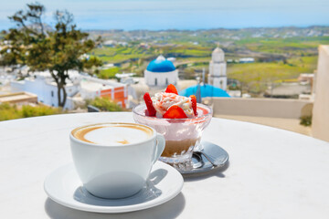 Cup of coffee with dessert on the table in a cafe in Pyrgos town, Santorini island, Greece