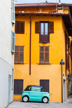 Old colorful architecture in Como, Italy. Windows with wooden shutters. Green car paked on the street. Famous travel destination.
