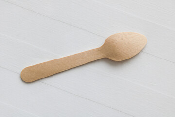 Close-up shot of a wooden spoon in an upside-down position, isolated on a white wooden background.