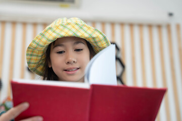 Smiling school asian girl reading a book in classroom