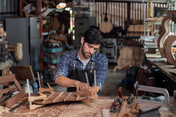Luthier creating a guitar, clamps on the body of a guitar under construction improving glue adhesion.
