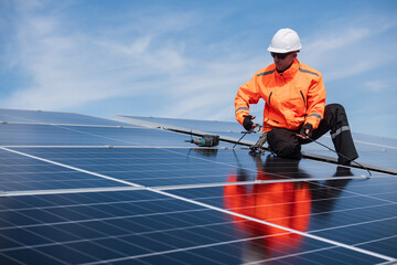 Technician installing solar panels on factory roof for green energy. A skilled technician in safety gear is working on a solar panel installation on rooftop.