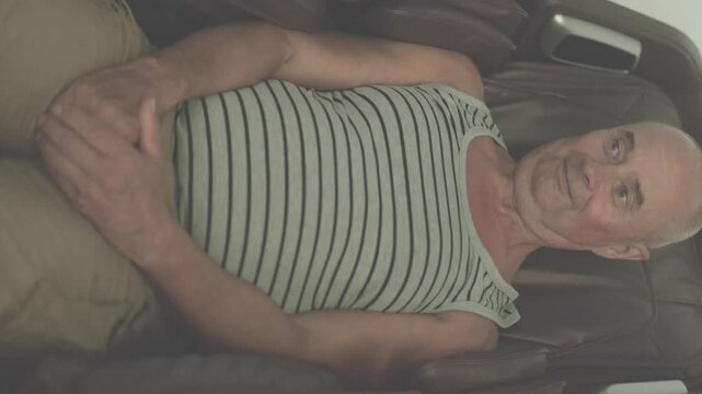 Happy mature charismatic man relaxing in modern automatic massage chair home or spa, senior 65 years old, feeling relief and comfort, age-related changes, mental human health, optimism in adulthood