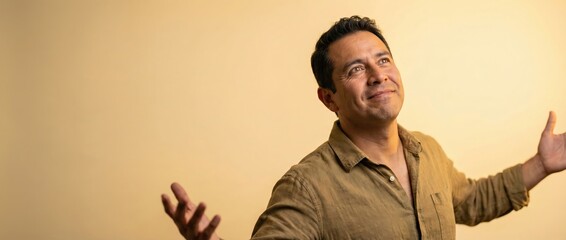 Hispanic man looking up with open arms, hopeful and inspired Adult male with a warm smile, celebrating success or dreaming