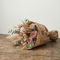 Beautiful dried flower bouquet with protea and roses in craft paper on wooden table for rustic interior decoration