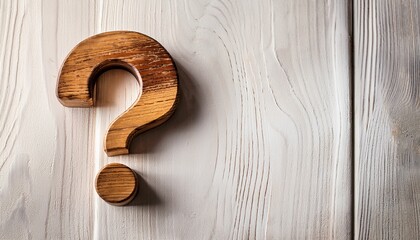 a wooden question mark symbol rests on a rustic white textured surface