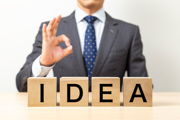 「IDEA」と書かれたブロックとOKポーズをするビジネスマン