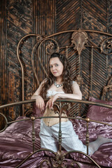 Beautiful sensual woman wears vintage underwear sitting on the metal bed