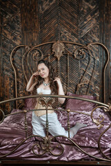 Beautiful sensual woman wears vintage underwear sitting on the metal bed