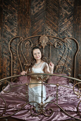 Beautiful sensual woman wears vintage underwear sitting on the metal bed