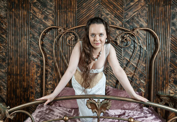 Beautiful sensual woman wears vintage underwear sitting on the metal bed