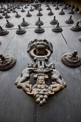 The Cathedral of Lima features a masterful display of colonial craftsmanship, particularly in the intricate metalwork of its massive wooden doors. These ornate bronze knockers and decorative studs