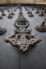 The Cathedral of Lima features a masterful display of colonial craftsmanship, particularly in the intricate metalwork of its massive wooden doors. These ornate bronze knockers and decorative studs