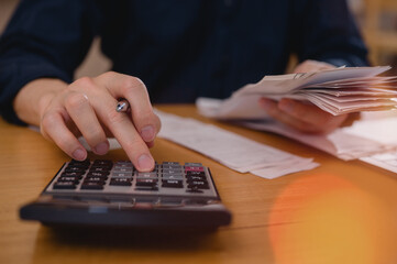 Businessman hand using calculator to budgeting and tax calculation monthly expenses. budget management and accounting on table. Business finance accounting banking concept.