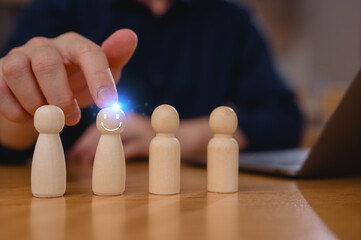 Choosing the Right Candidate Employee Selection Process. Businessman leader holding and choosing wooden people from a group of employees while working on laptop computer in office