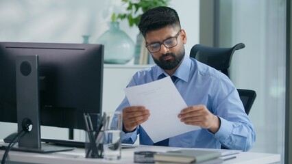 Indian businessman Arabian business man ethnic male worker guy professional entrepreneur working in office typing computer checking documents work process focused busy job online at workplace table