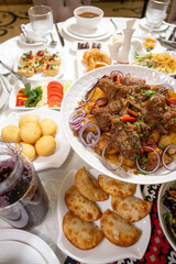 Close-up of Kuirdak with potatoes and bread rolls on set table