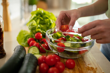 Adult focused on preparing fresh salad in home kitchen