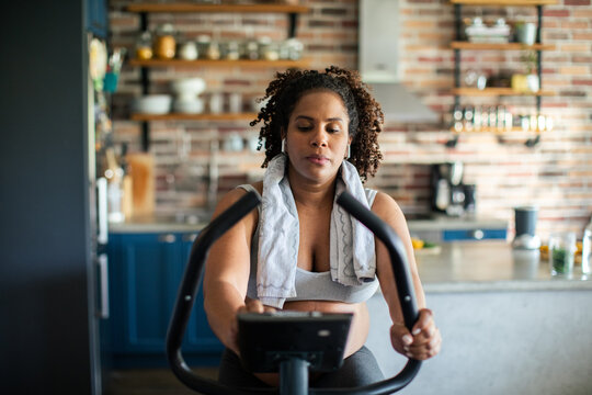 Adult woman focused on indoor cycling workout in home kitchen