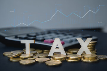 Taxation financial year preparation, wooden word TAX and gold coins with blurred calculator in background